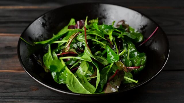 chef hands mixing green salad with arugula, spinach, olive oil. healthy lifestyle concept 