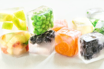 Frozen ice cubes with vegetables, berries, herbs on a white background. Home preservation of food during the quarantine period. Home food concept - obrazy, fototapety, plakaty