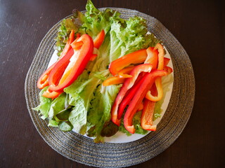 Red bell pepper and green salad leaves. Vegetables on a plate. 

