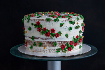 White cake with red flowers on a dark background.
