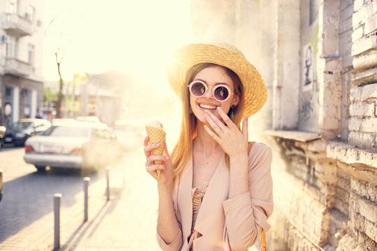 Pretty woman in sunglasses and a hat on the street walk with ice cream
