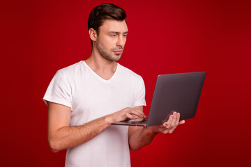 Photo portrait of young programmer working with laptop concentrated focused isolated vibrant red color background