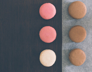 Delicious chocolate, strawberry and vanilla macaroons arranged on a wooden table in a contemporary design with copy space
