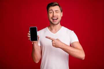Photo portrait of young man showing finger on cellphone copyspace winking blinking isolated vivid...