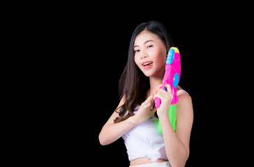 Portrait cheerful young asian woman Wearing a yellow tank top ,holding plastic water gun Smiling and having fun playing in the water Songkran festival, Songkran Thailand. isolated on black background.