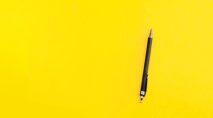 Black metal nib ballpoint pen on yellow background with copy space text place. School education. Tool of author writer. Banner with automatic pencil. Stationery shop advertising. Simple business card