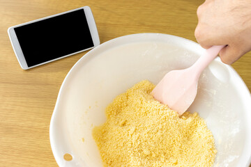 スマートフォンを見てクッキーを作る男性のイメージ