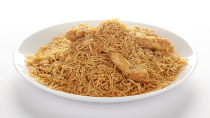 Indian spicy snacks (Namkeen) - Bikaneri Besan Bhujia in a white plate, made with chickpea flour (Besan), side view, against the white background.