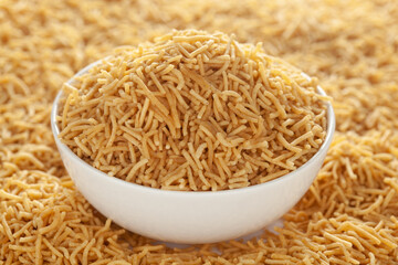 Indian spicy snacks (Namkeen) - Bikaneri Besan Bhujia in a white bowl, made with chickpea flour (Besan), side view.