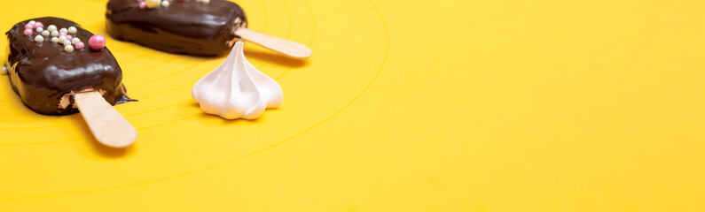 Marshmallow on a popsicle stick covered in chocolate with pink meringue on a yellow background. Banner. Selective focus.