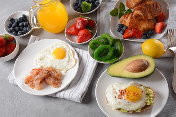 Healthy breakfast. Toast with avocado and egg, bacon and eggs, fresh and dried fruits, fresh juice