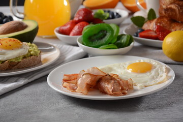 Healthy breakfast. Toast with avocado and egg, bacon and eggs, fresh and dried fruits, fresh juice