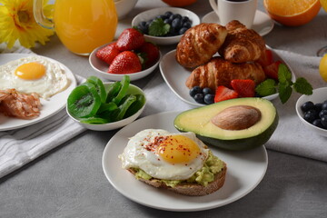 Healthy breakfast. Toast with avocado and egg, bacon and eggs, fresh and dried fruits, fresh juice