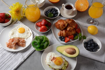 Fototapeta na wymiar Healthy breakfast. Toast with avocado and egg, bacon and eggs, fresh and dried fruits, fresh juice