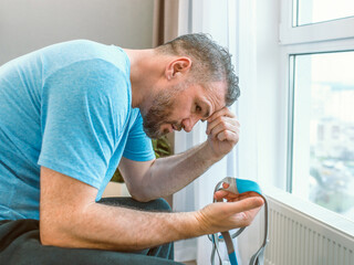 Unhappy shocked man with chronic breathing issues surprised by using  CPAP machine sitting on the bed in bedroom. Healthcare, CPAP, Obstructive sleep apnea therapy, snoring concept