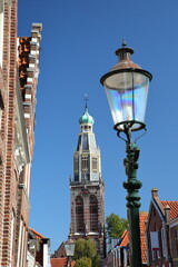 The clock tower of Zuiderkerk (or St Pancraskerk) with crooked historic houses in the foreground,...