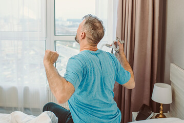 Happy rested man with chronic breathing issues after using  CPAP machine sitting on the bed in...