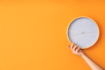 Female hand with clock on color wall