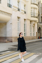 Beautiful woman in a black dress on a background of an urban landscape