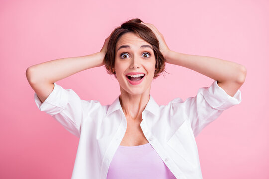 Photo portrait of happy surprised female student smiling keeping head with hands isolated on pink pastel color background