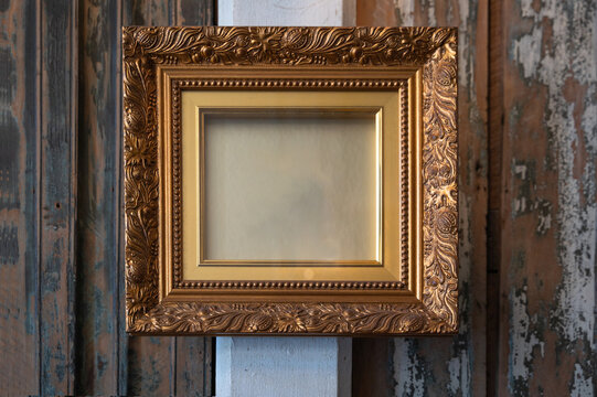 Beautiful antique golden wooden picture frame interior with blank space for text and advertising on olive green color old wooden wall vintage style decoration