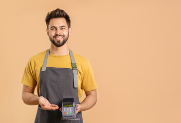 Young waiter with payment terminal on color background