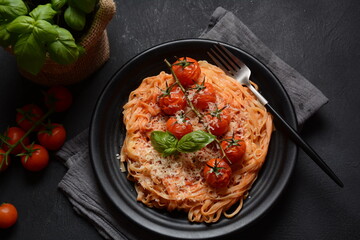 Spaghetti pasta with cherry tomatoes garnished with basil leaf