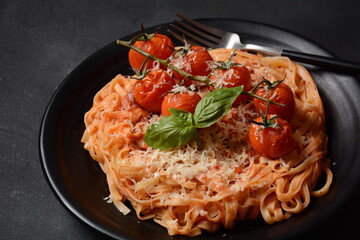 Spaghetti pasta with cherry tomatoes garnished with basil leaf