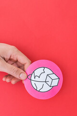 Male hand holding international trade shape symbol, on red background.