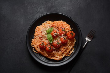 Spaghetti pasta with cherry tomatoes garnished with basil leaf