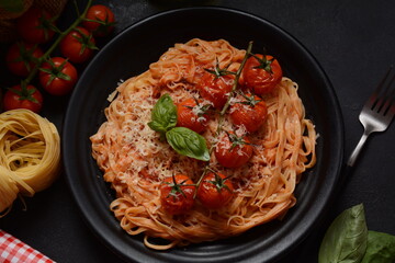 Spaghetti pasta with cherry tomatoes garnished with basil leaf
