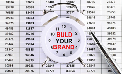 Business concept. text Build Your Brand on alarm clock on chart background