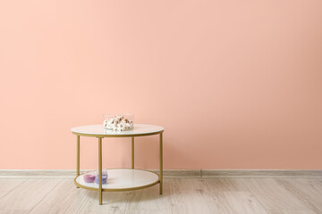Stylish table with cotton flowers near color wall