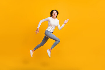 Fototapeta na wymiar Full size profile photo of optimistic girl jump run wear sweater jeans sneakers isolated on yellow color background