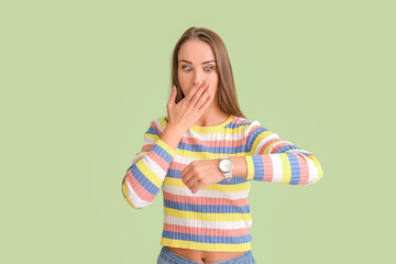 Shocked woman with wristwatch on color background
