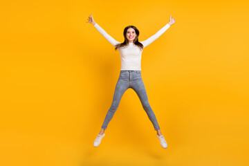 Fototapeta na wymiar Full size photo of optimistic nice girl jump wear sweater jeans sneakers isolated on yellow color background