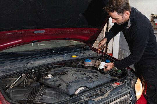 Mechanic looking at oil level in the engine of the car. Concept of automobile mechanics.