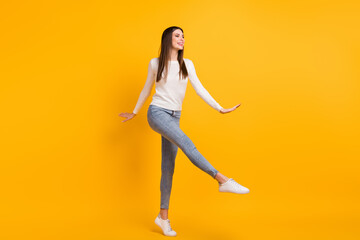 Full size photo of optimistic girl dance wear sweater jeans sneakers isolated on yellow color background