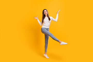 Fototapeta na wymiar Full size photo of optimistic brunette girl dance wear sweater jeans sneakers isolated on yellow color background