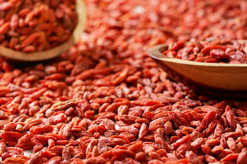 Dry goji berries in small wooden bowls, scattered on desk below