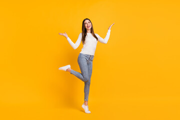 Fototapeta na wymiar Full size photo of optimistic brunette girl dance wear white sweater jeans sneakers isolated on yellow color background