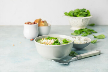 Bowl with tasty spinach soup on light background