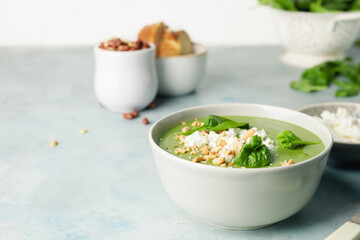 Bowl with tasty spinach soup on light background