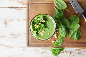 Glass of healthy spinach smoothie on wooden background