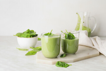 Glasses of healthy spinach smoothie on light table