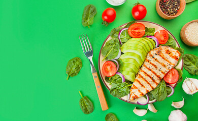Grilled chicken breast and fresh vegetable salad with spinach leaves, avocado and tomatoes on a green background. Salad of greens with meat. Ketogen diet. Dietary nutrition. Copy space.
