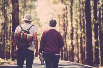 Senior couple enjoy outdoor leisure activity together walking close on the road with nature forest woods around - people free and retired elderly active lifestyle concept