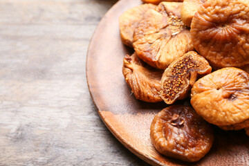 Plate with tasty dried figs on wooden table, closeup