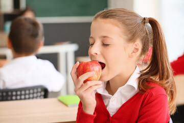 Schoolgirl eating apple in classroom