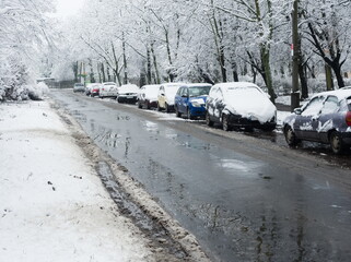 Snowy cars standing along the street. Winter cityscape. Snow-covered cars